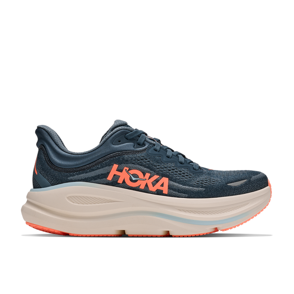 A HOKA running shoe in navy blue with a thick beige midsole and bright orange accents, shown from the side on a white background.