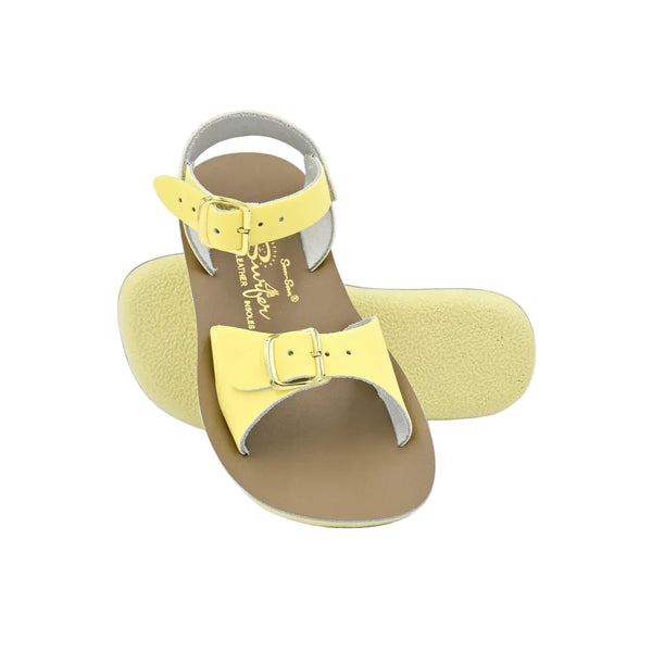 Sun San yellow and brown sandal with a bow on a light gray background